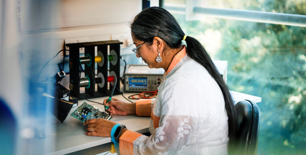 Woman soldering circuit board in a electronics lab